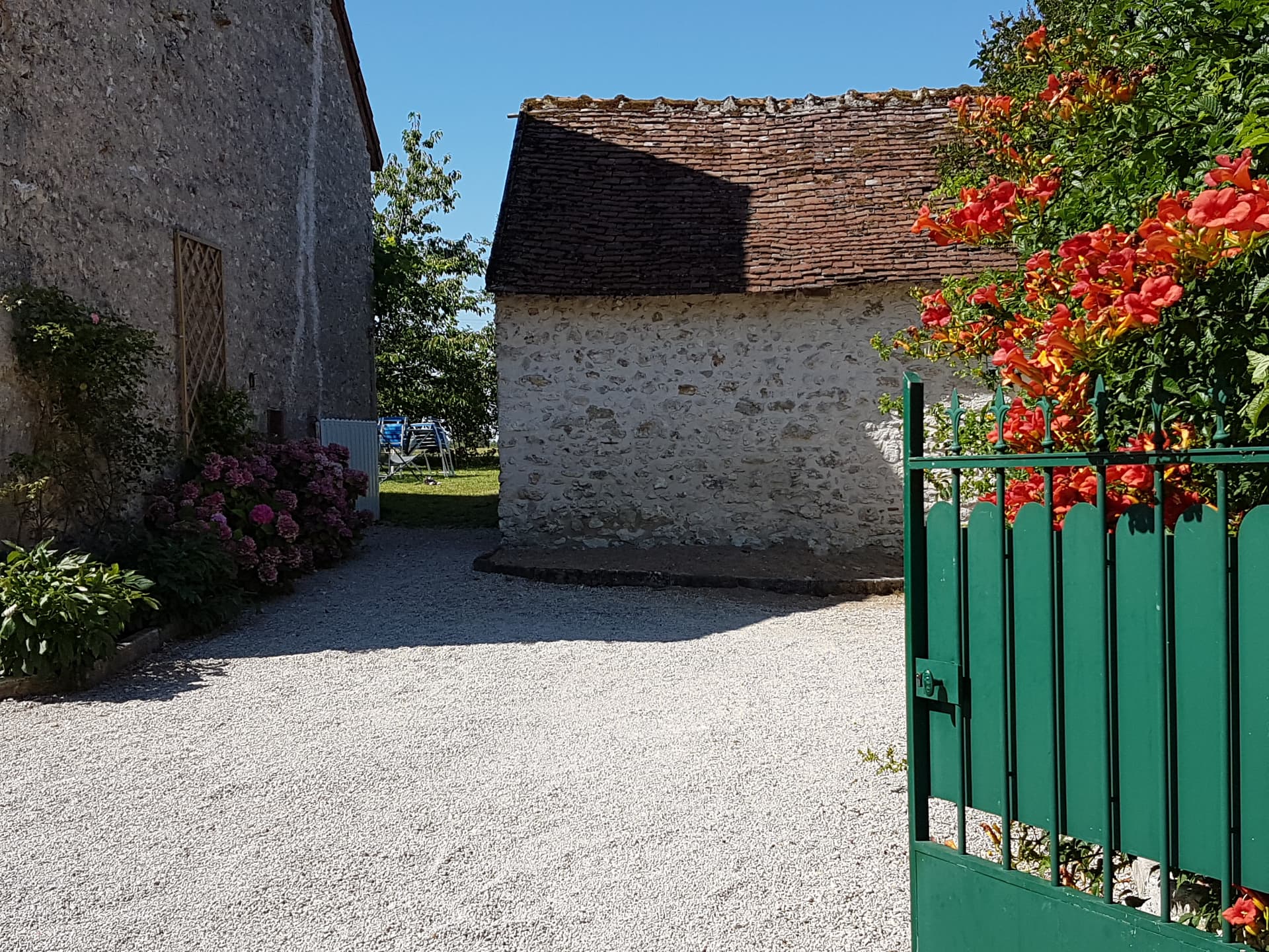 Gîte Le Petit Verger - Entrée avec portail vert et dépendances en pierre