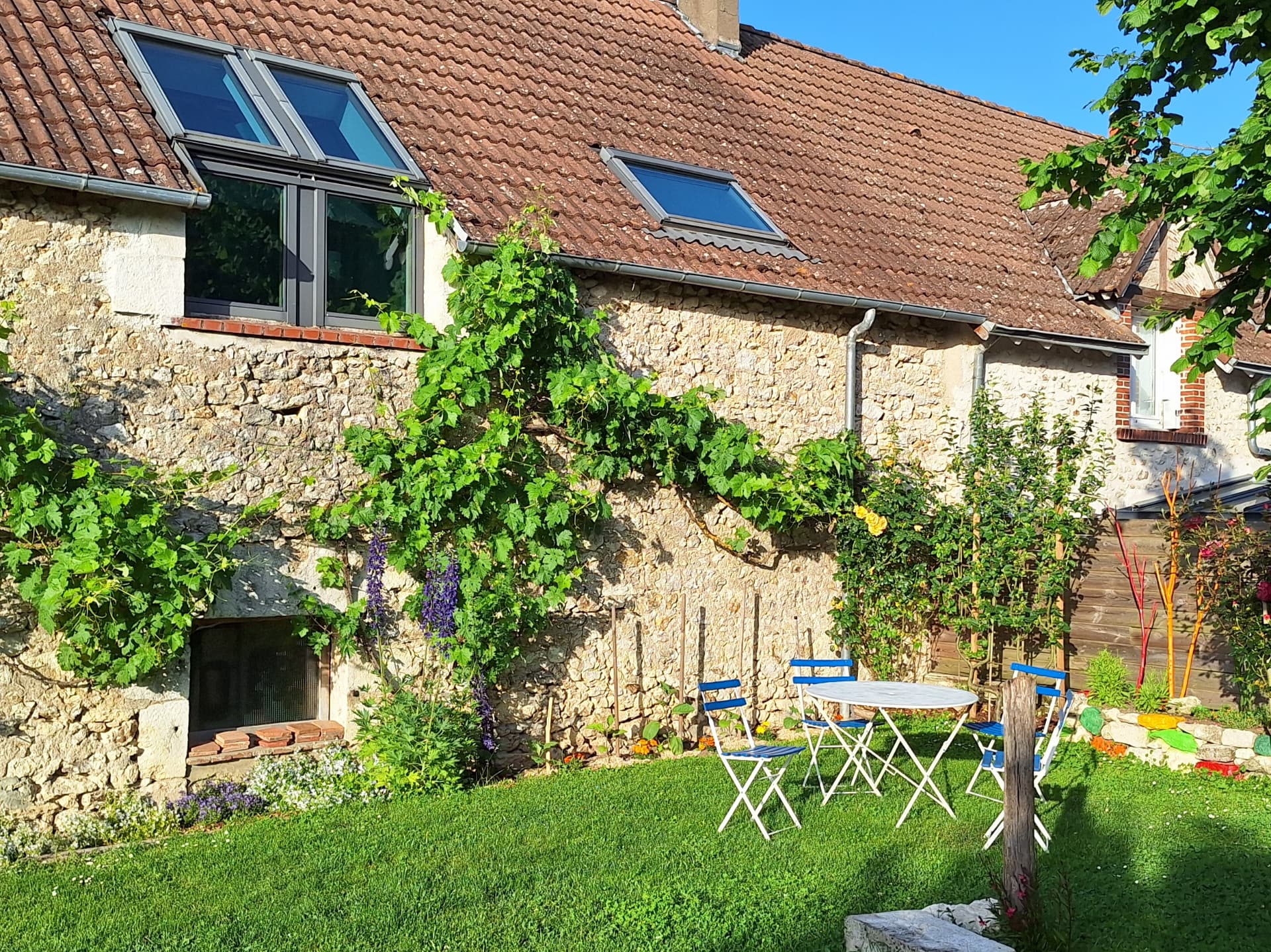 Gîte Le Petit Verger - Façade en pierre et coin repas du jardin privatif