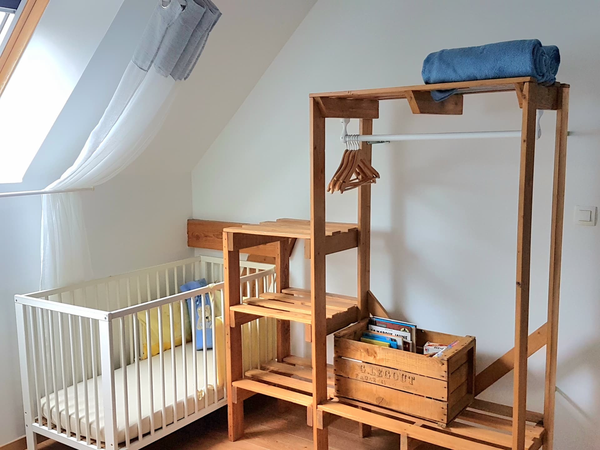 Gîte Le Petit Verger - Lit bébé et rangements en bois dans la chambre familiale